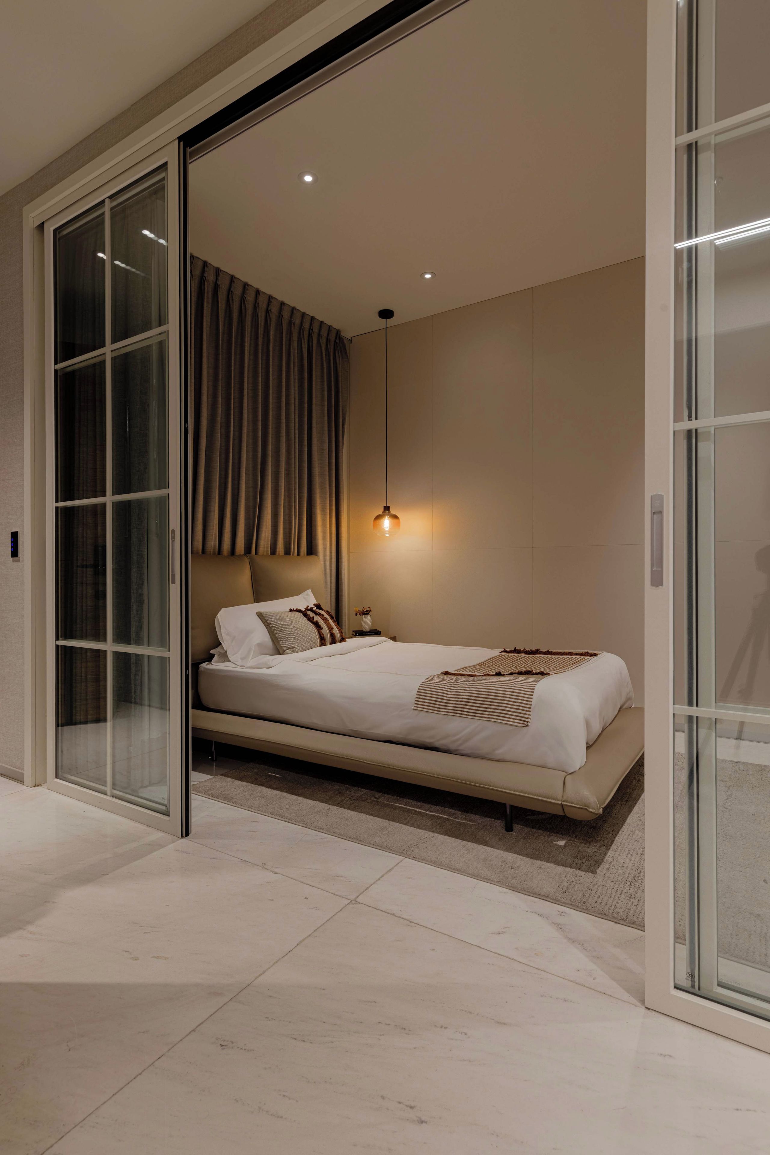 Een moderne slaapkamer met een bed, een nachtkastje, een lamp en een schuifdeur naar een balkon.