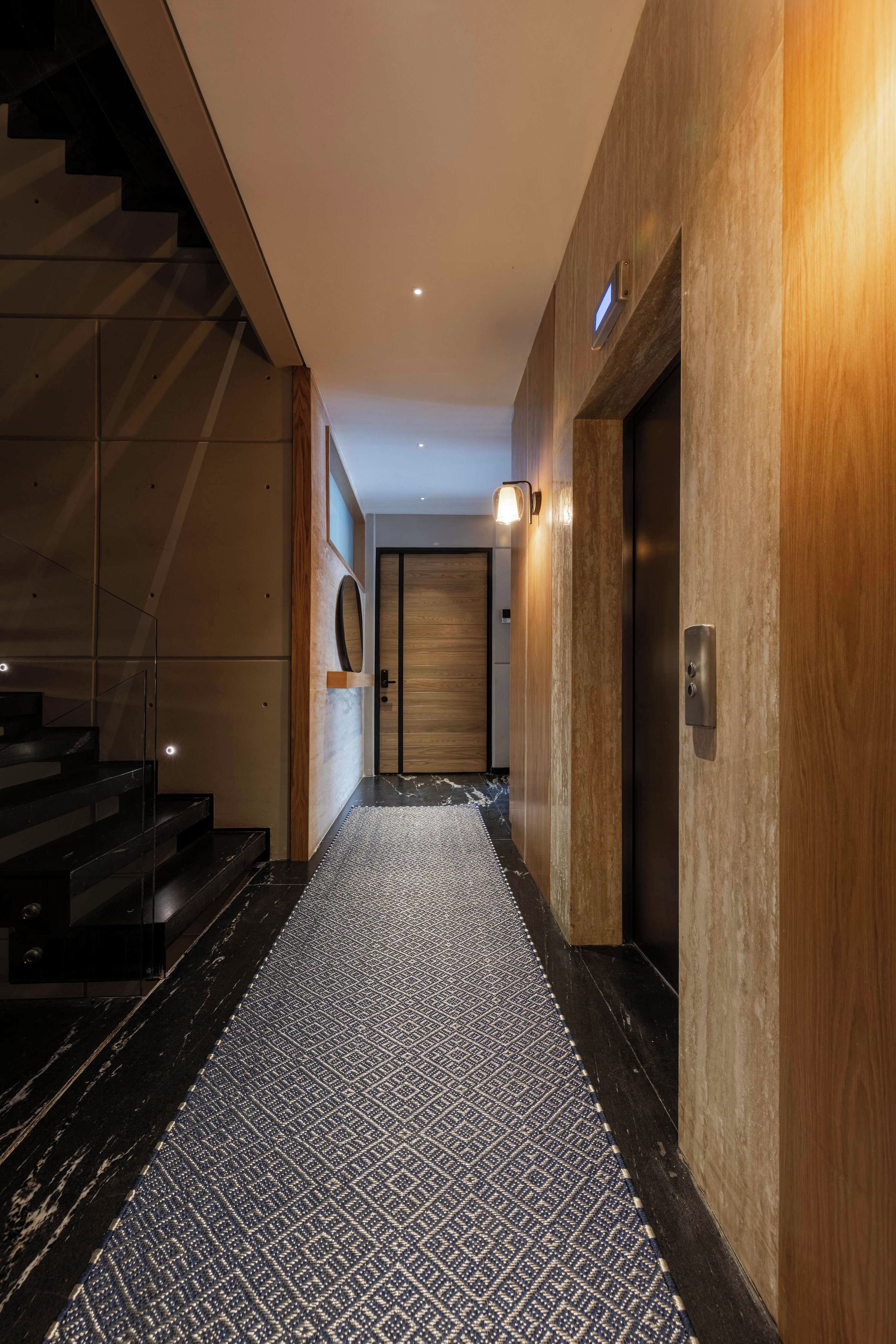 Ein modernes Interieur mit einer Treppe, einem gemusterten Teppich und einer Holzwand.