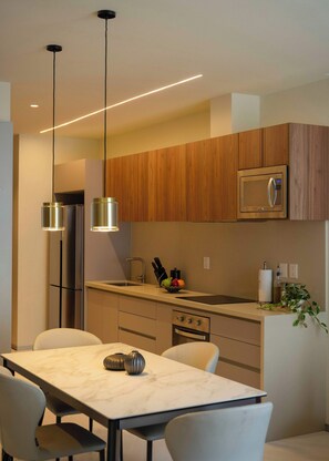 A modern kitchen with wooden cabinets, stainless steel appliances, and a marble countertop. - Family 2BR Apartment with Quiet Courtyard Balcony in Polanco (Ciudad de México)