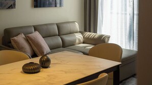 Moderni olohuone, jossa on sohva, ruokapöytä ja riippuvalaisin.
