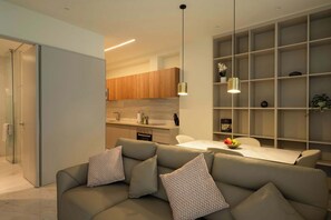 Ein modernes Wohnzimmer mit einer Couch, einem Esstisch und einer Küche im Hintergrund.