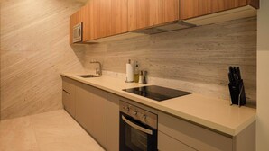 Eine moderne Küche mit Holzschränken, einem Backofen, einer Spüle und einem schwarzen Induktionskochfeld.