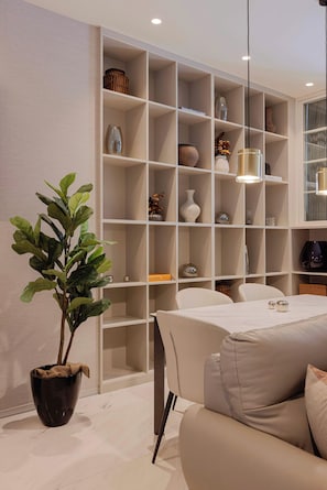 A modern living room with a sofa, a dining table, and a large built-in shelving unit with various decorative items. - Deluxe 1BR Apartment with Street-Facing Terrace in Polanco (Ciudad de México)