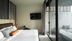 Ein modernes Hotelzimmer mit einem großen Bett, einem an der Wand befestigten Flachbildfernseher und einer Schiebetür zu einem Sitzbereich im Freien.