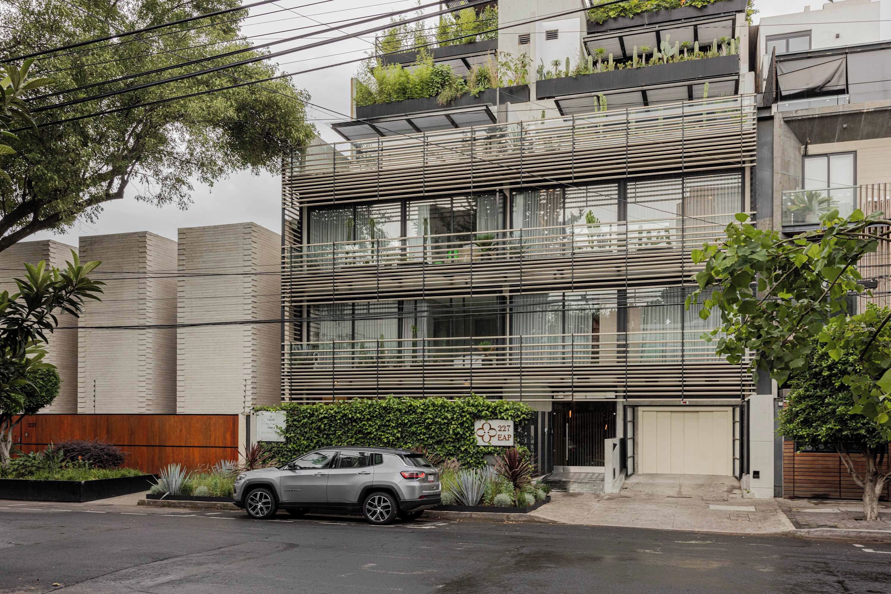 A modern multi-story building with a car parked in front.