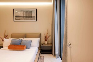A hotel room with a bed, a nightstand, a framed picture on the wall, and a door with curtains. - Garden 1BR Apartment with Interior Terrace in Polanco (Ciudad de México)
