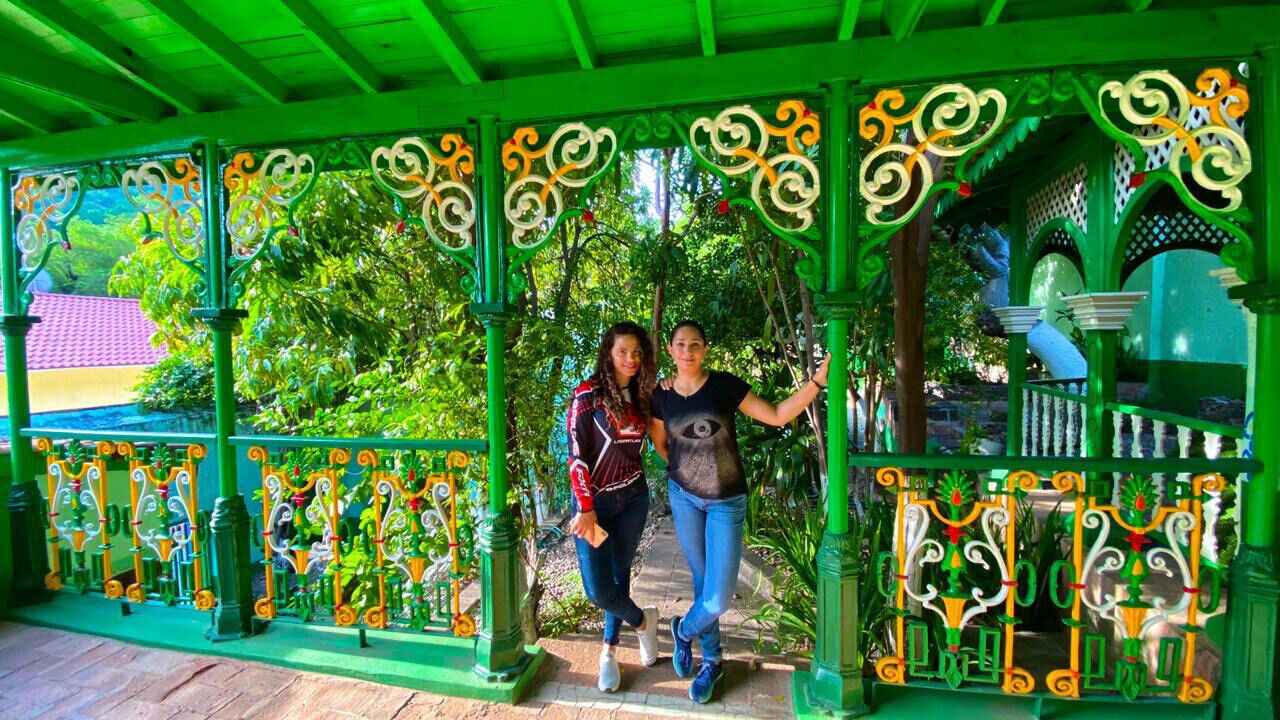 A covered walkway with ornate metal railings and a green roof.