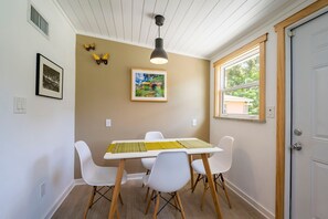 A dining area with a table, chairs, a pendant light, and artwork on the wall. - Coastal Cocoanut Cottage ~ Whitaker Bayou~Bay (Sarasota)