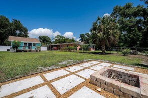 A residential area with a grassy lawn, a paved patio area, and a house with a porch. - Coastal Cocoanut Cottage ~ Whitaker Bayou~Bay (Sarasota)