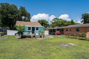 A residential area with two houses, one with a blue exterior and the other with a red exterior, surrounded by a grassy yard and trees. - Coastal Cocoanut Cottage ~ Whitaker Bayou~Bay (Sarasota)