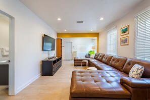 Ein modernes Wohnzimmer mit einer Ledersofa, einem Fernseher und einem Holzkasten.