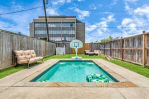 Ein Garten mit Swimmingpool, Basketballkorb und Holzzaun.