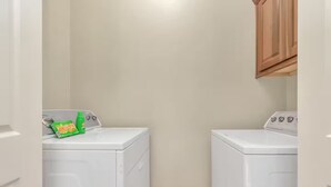 A laundry room with two white front-loading washing machines and a cabinet above one of them. - Gold&Brown!Oasis Pool HugeSuites Sleep10+!Galleria (Houston)