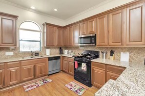 A kitchen with wooden cabinets, a microwave, stove, dishwasher, and granite countertops. - Gold&Brown!Oasis Pool HugeSuites Sleep10+!Galleria (Houston)