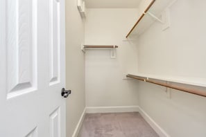 Ein kleiner, abgeschlossener Raum mit einer weißen Tür, einem Holztürgriff, einer weißen Wand und einem Holzbalken an der Decke.