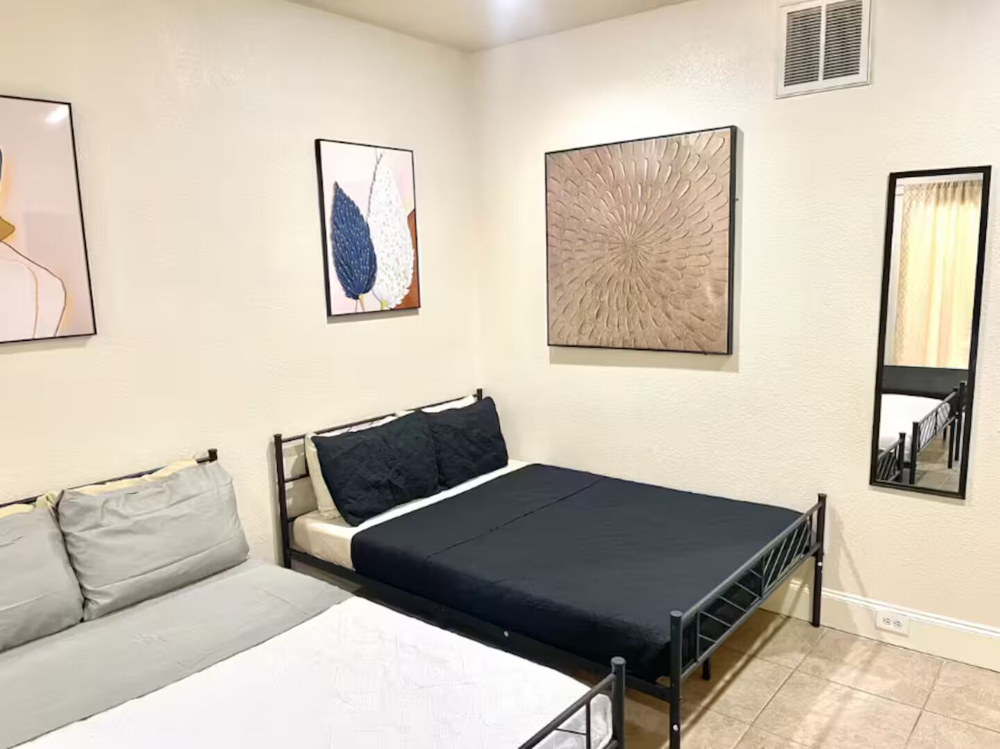 A bedroom with a bed, a sofa, and two wall-mounted artworks.