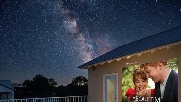 A deck with outdoor seating and a large screen displaying an advertisement. - 10 Min WalkTo 30A Beach Rooftop View & Cinema (Santa Rosa Beach)