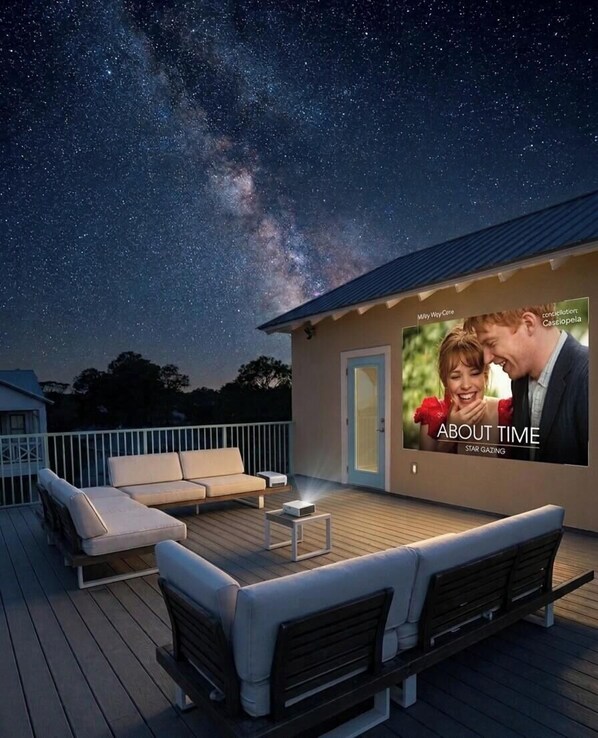 Eine Terrasse mit Sitzgelegenheiten und einem großen Bildschirm, der eine Werbung zeigt.