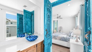 A bedroom with a bed, a dresser, a mirror, and a bathroom with a sink and a blue bowl. - 10 Min WalkTo 30A Beach Rooftop View & Cinema (Santa Rosa Beach)