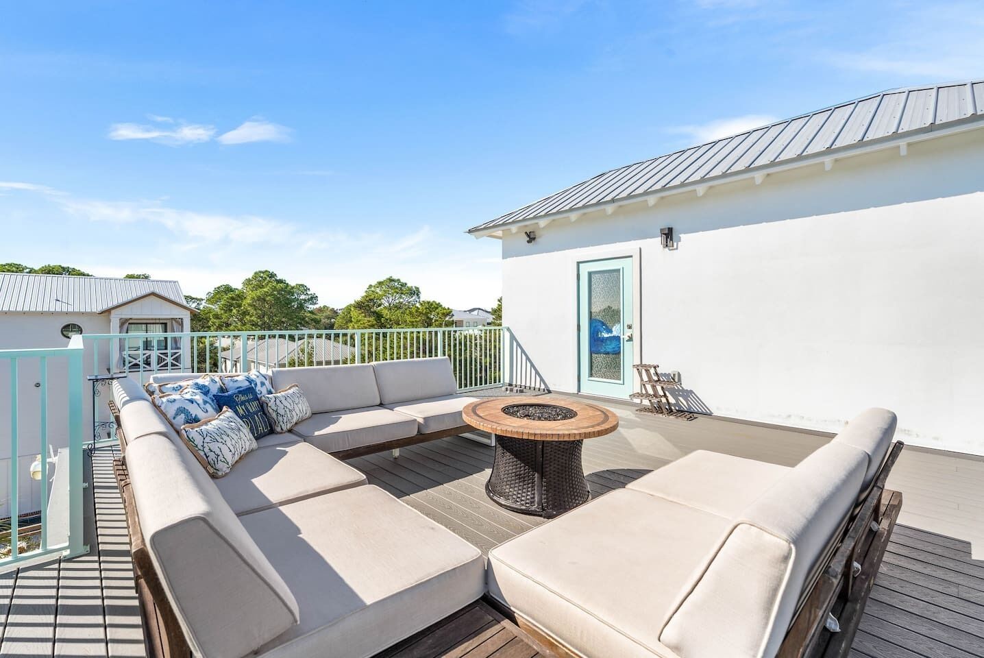 A rooftop deck with a sofa set, a round table, and a door with a frosted glass panel.