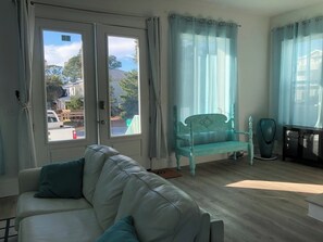A living room with a white sofa, a turquoise chair, and a wooden floor. - 10 Min WalkTo 30A Beach Rooftop View & Cinema (Santa Rosa Beach)