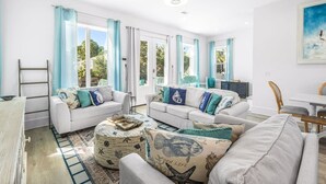A spacious living room with two white sofas, a coffee table, and a dining area with a table and chairs. - 10 Min WalkTo 30A Beach Rooftop View & Cinema (Santa Rosa Beach)