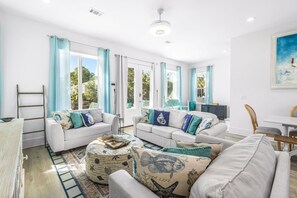 Ein geräumiges Wohnzimmer mit zwei weißen Sofas, einem Couchtisch und einem Essbereich mit Tisch und Stühlen.