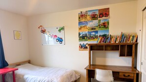 A bedroom with a single bed, a desk with a chair, a bookshelf, and a wall decorated with children's drawings and photos. - Gather in the Saddle - Spacious 3BR (Cheyenne)