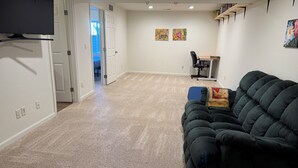 A living room with a dark green sofa, a small table with a chair, and a bookshelf against the wall. - Gather in the Saddle - Spacious 3BR (Cheyenne)