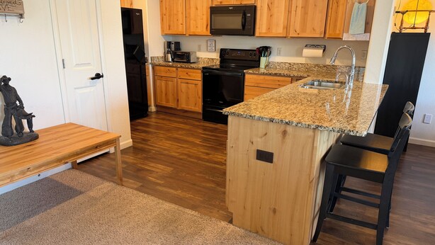 A kitchen with wooden cabinets, a granite countertop, a built-in oven, a microwave, and a sink. - Gather in the Saddle - Spacious 3BR (Cheyenne)
