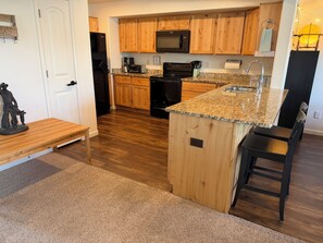 A kitchen with wooden cabinets, a granite countertop, a built-in oven, a microwave, and a sink. - Gather in the Saddle - Spacious 3BR (Cheyenne)
