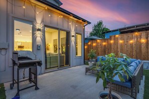 Ein modernes Haus mit Terrasse, Sitzgelegenheiten im Freien und einem Grill.