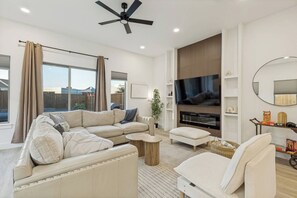 Ein modernes Wohnzimmer mit einem Ecksofa, einem Flachbildfernseher und einem Kamin.