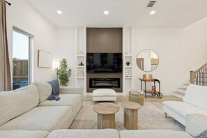 Ein modernes Wohnzimmer mit einer Couch, einem Couchtisch und einem an der Wand befestigten Flachbildfernseher.