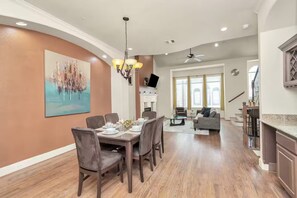 A modern dining area with a large table set for four, a chandelier, and a painting on the wall. - 2UNITS!20+ Guests!King Bed!2 Pools!Free Parking (Houston)