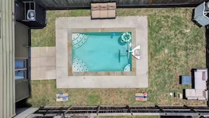 Ein rechteckiger Pool mit Whirlpool, umgeben von einer Betonplattform und zwei Liegestühlen.