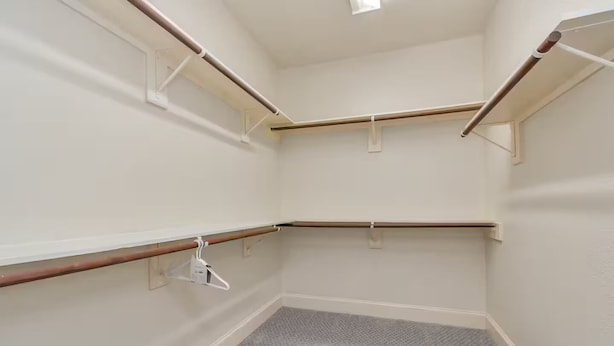 Ein Eckzimmer mit grauem Teppich, weißen Wänden und Holzbalken.