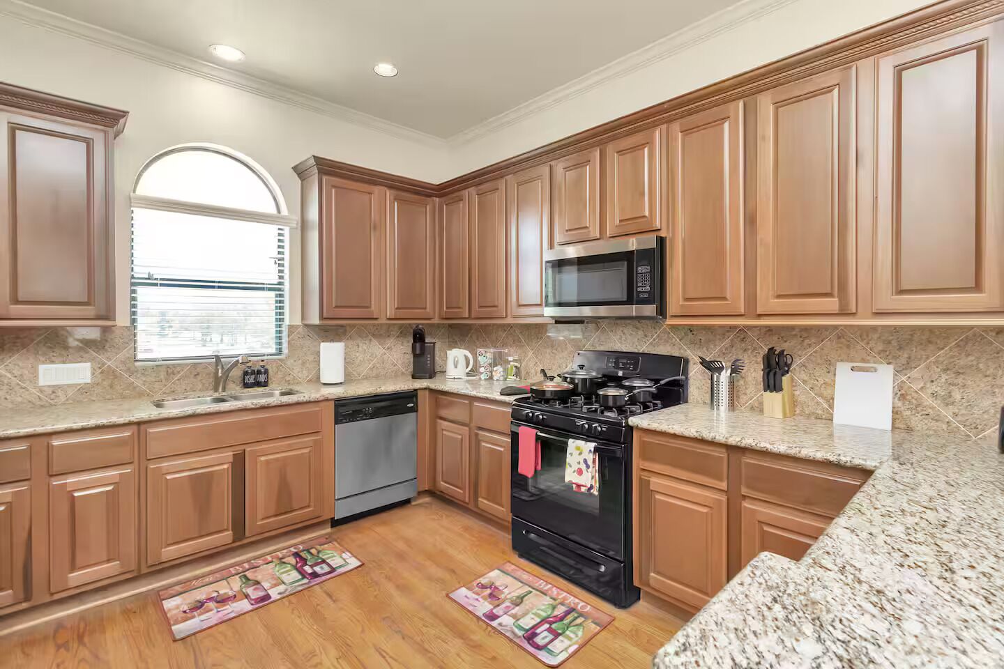 A kitchen with wooden cabinets, a microwave, stove, dishwasher, and granite countertops.