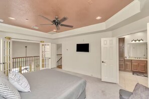 A bedroom with a bed, a ceiling fan, a TV, and a view into the kitchen. - 2UNITS!20+ Guests!King Bed!2 Pools!Free Parking (Houston)