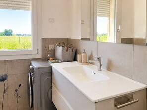 Une salle de bain moderne avec un grand miroir, un lavabo blanc et un lave-linge.