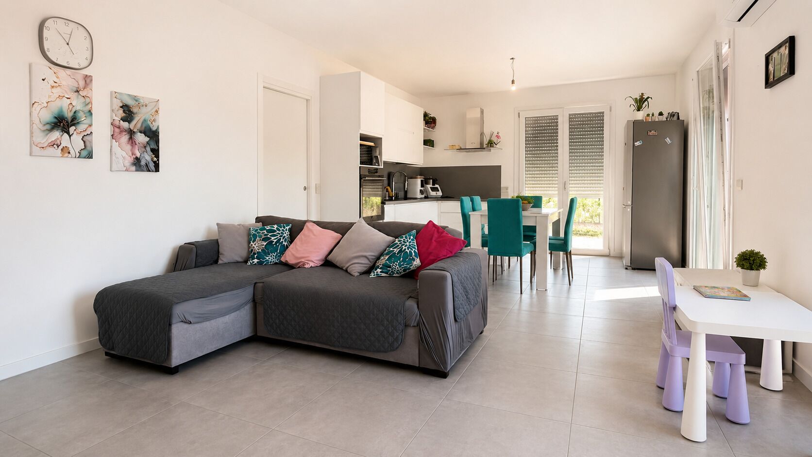 A modern living space with a sectional sofa, a dining area, and a kitchen.