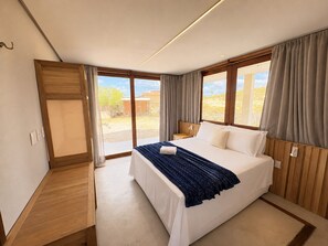 A bedroom with a large bed, a wooden bench, and a view of the outdoors. - Hosts BR - Acayu Piscina e Rooftop (Cajueiro da Praia)