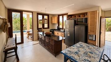 A modern kitchen with a central island, wooden cabinets, and a dining area with a patterned table.