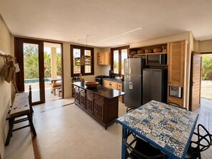 A modern kitchen with a central island, wooden cabinets, and a dining area with a patterned table.