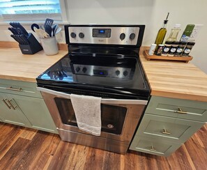 A stainless steel Whirlpool gas range with a digital display, a wooden countertop, and a set of kitchen utensils.