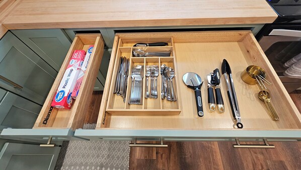 A drawer with various kitchen utensils and a box of plastic wrap. - Charming, streamside, 3-bedroom country house in Confluence! (Confluence)