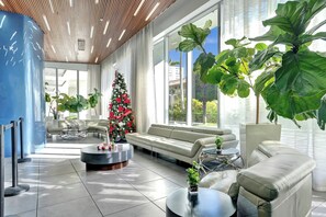 A modern lobby with a Christmas tree, leather sofas, and large windows. - *Beachwalk Resort Spacious 2 Bedroom 2 Bathroom Apt (Hallandale Beach)
