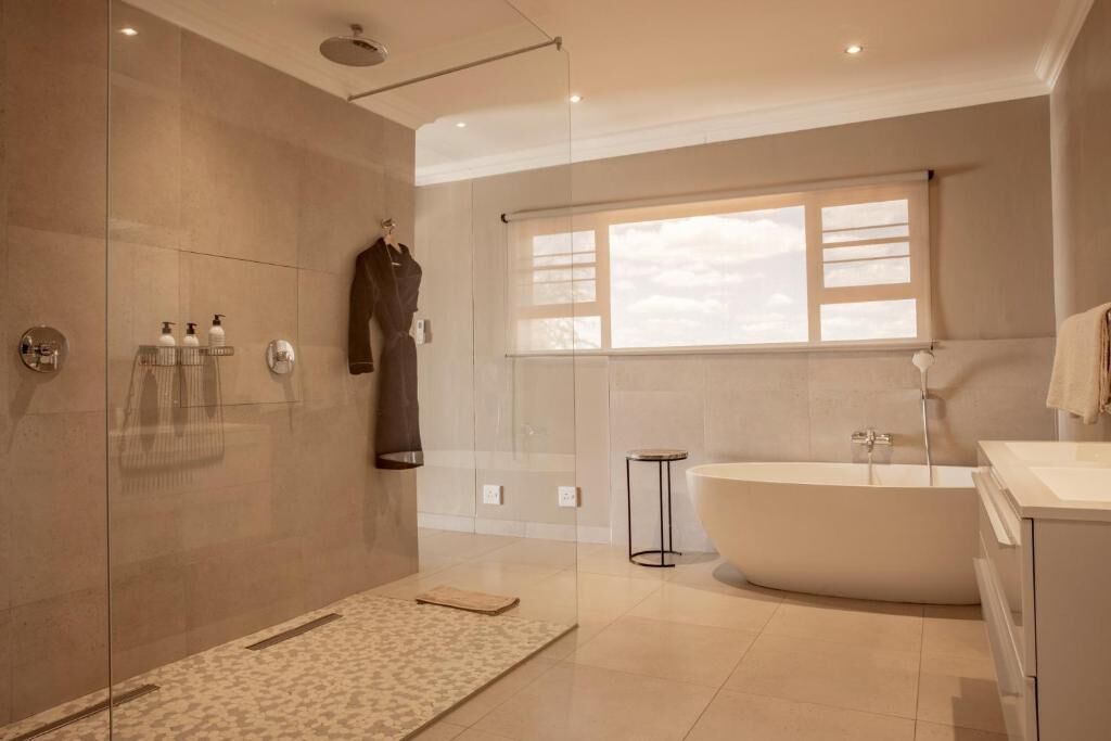 Un baño moderno con ducha de vidrio, una bañera independiente y un amplio ventanal que proporciona luz natural.