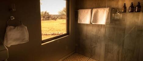 A room with a window, towels, and bottles on a shelf.