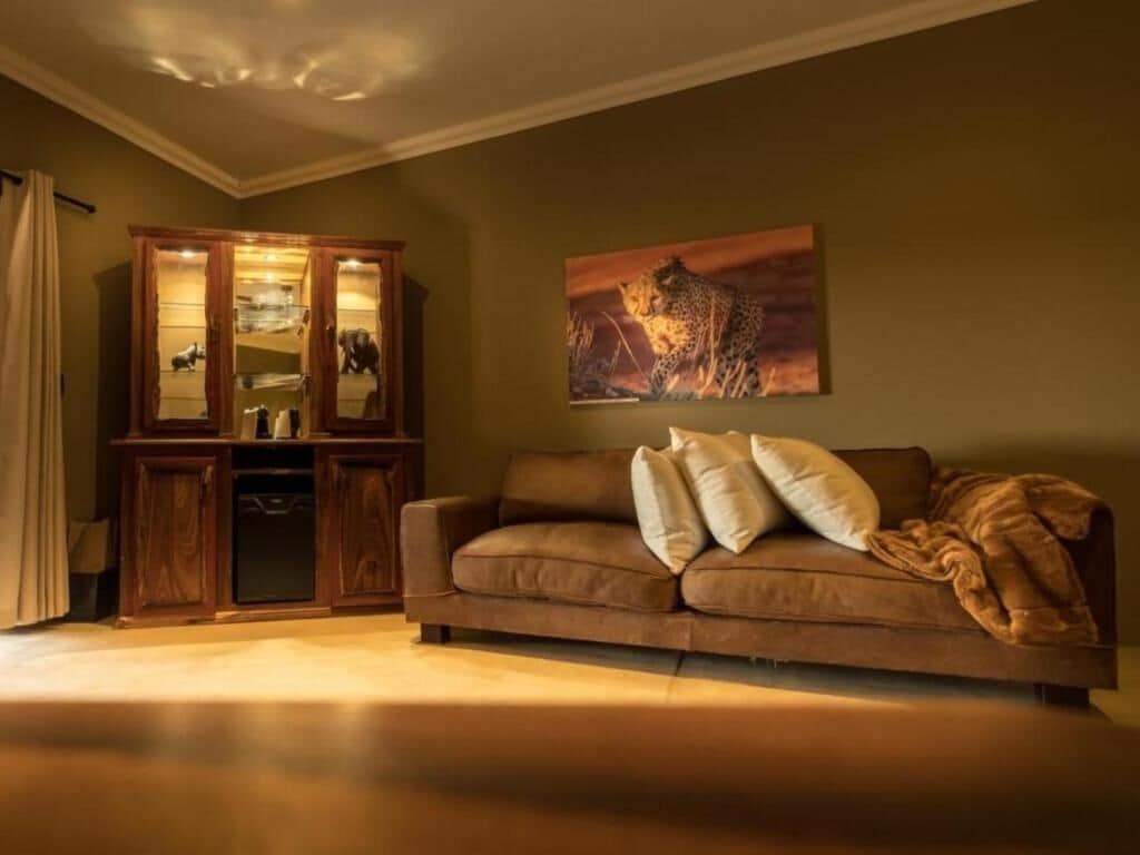 Una sala de estar con un sofá marrón, un mueble de madera y un cuadro de un guepardo.